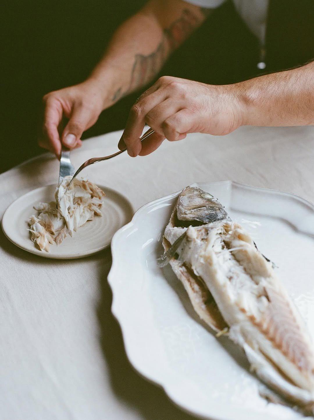Un poisson entier servi sur un plat blanc, levé à la fourchette